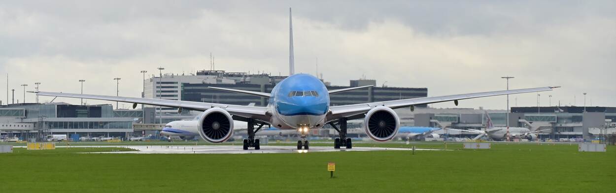 Vliegtuig van vooraf gezien op het vliegveld met contouren Schiphol op de achtergrond