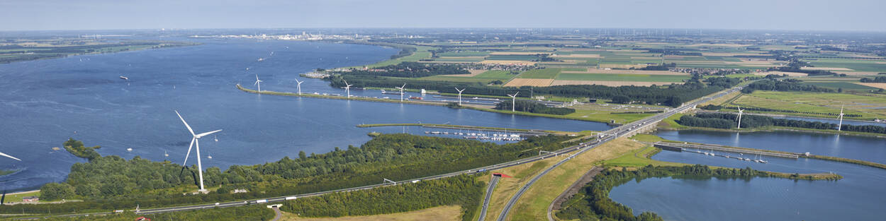 Landschap met wegen, water, windmolens en een haven