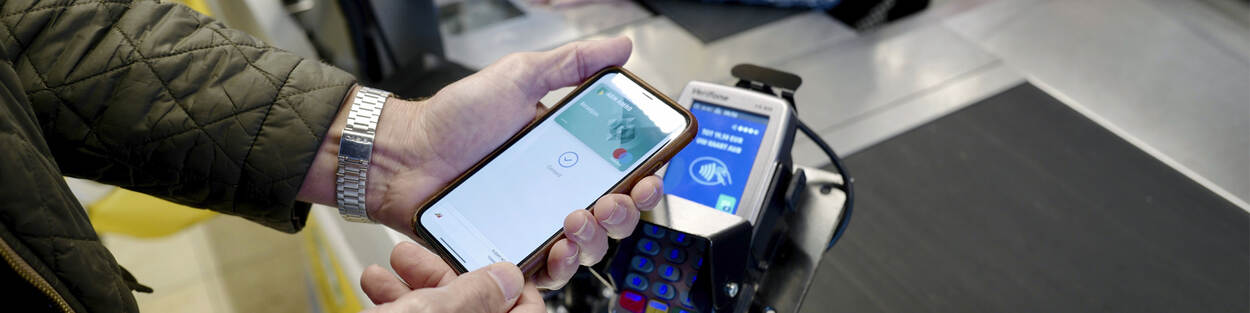 Persoon met telefoon in de hand pint met de telefoon bij de supermarkt