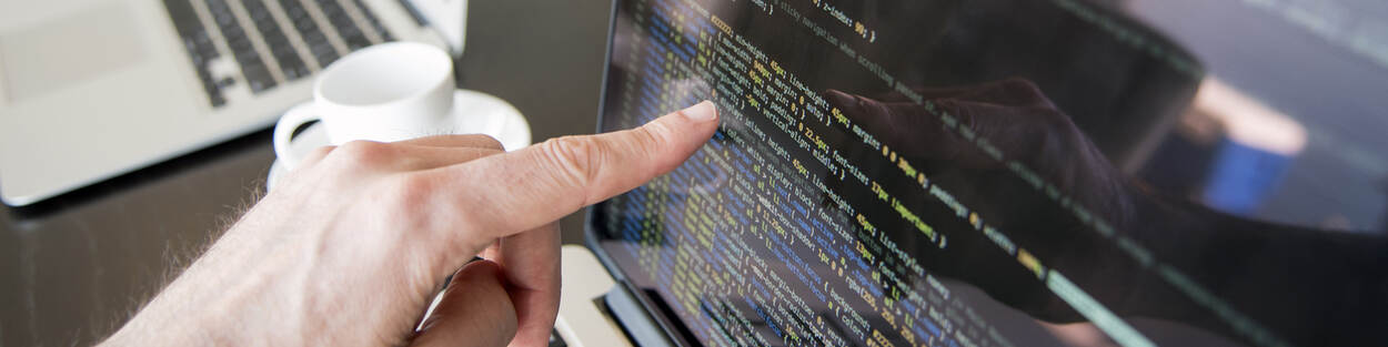 persoon achter een beeldscherm met diverse prompt-teksten MS-DOS terwijl vinger iets aanwijst