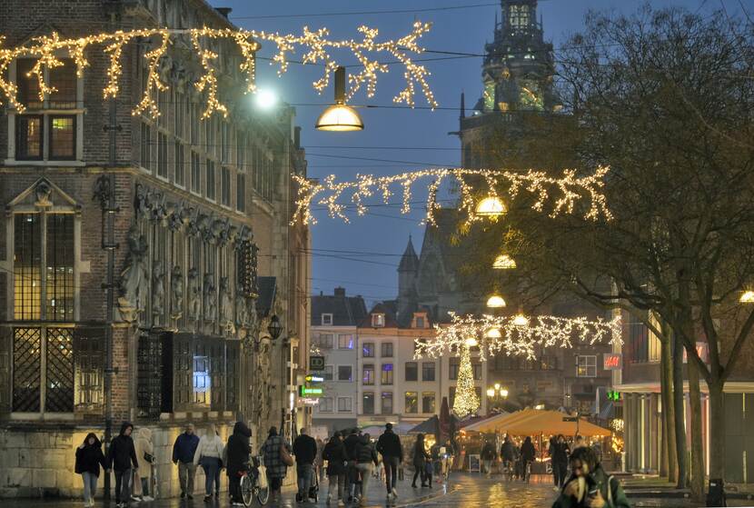 Mensen in winkelstraat met kerstverlichting