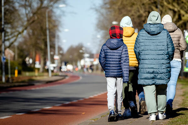 4 Vluchtelingen uit Oekraïne lopen richting opvangcentrum, van achteren gezien, ze hebben warme jassen en mutsen op