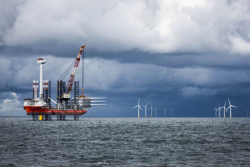 Boorplatform op zee met op de achtergrond ook windmolens
