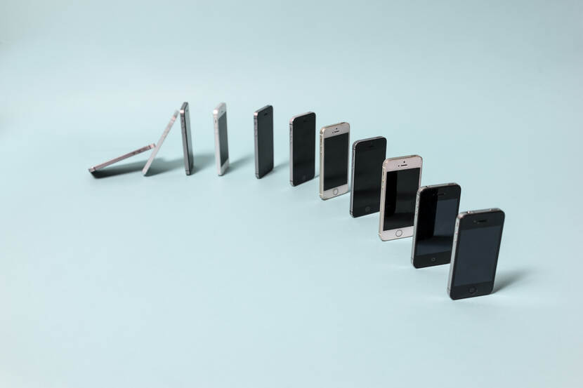 Rij telefoons die staan in een cirkel die omvallen als dominostenen