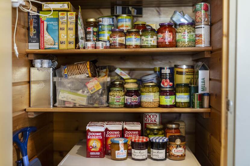 Voorraadkast met diverse potjes en blikjes groenten, pakken koffie, potjes jam, pindakaas, pakjes aardappelpuree