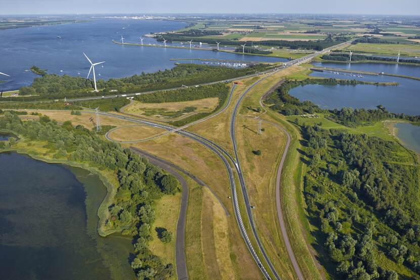 Landschap met wegen, water, windmolens en een haven