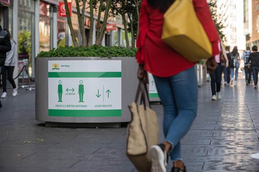 Mensen op straat met zichtbaar bord 'anderhalvemeter' afstand houden van elkaar (Coronaperiode)