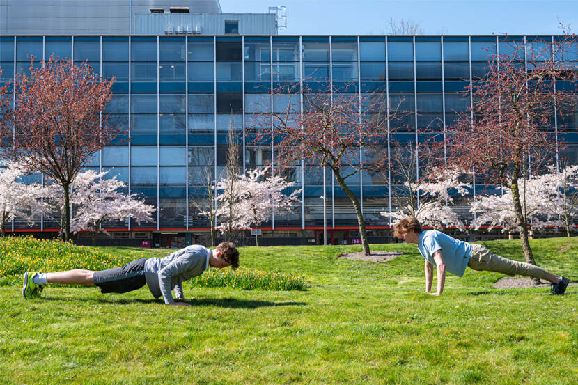 Sporters op een grasveld met op de achtergrond een gebouw